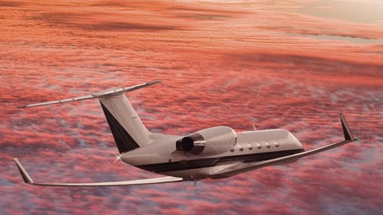Private business jet flying in red sky